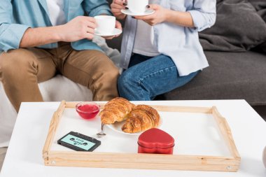 kanepede oturan ve evde kahvaltı sırasında kahve içme çiftin kırpılmış görünümü