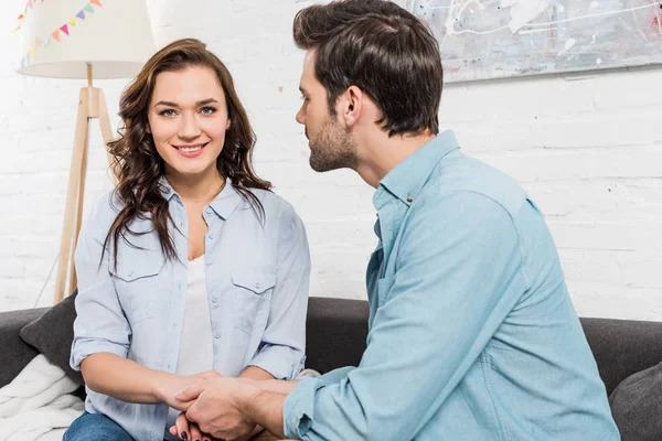 Couple Sitting Couch Holding Hands While Woman Looking Camera Home — Stock Photo, Image