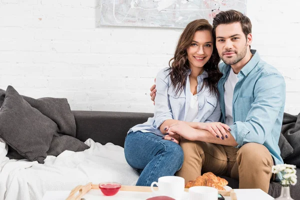 Couple Sitting Couch Looking Camera Embracing While Having Breakfast Home — Stock Photo, Image