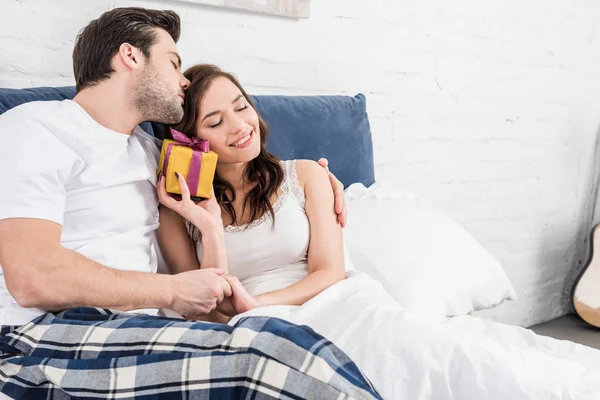 Pasangan Bahagia Berbaring Tempat Tidur Memeluk Dan Memegang Hadiah Ulang — Stok Foto