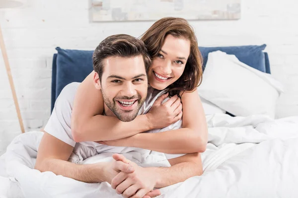Glückliches Paar Blickt Die Kamera Und Kuschelt Hause Bett — Stockfoto