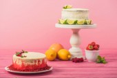 Kuchen mit Johannisbeeren und Minzblättern in der Nähe von Früchten und weißer Kuchen auf rosa Holzoberfläche isoliert auf rosa dekoriert