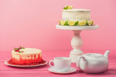 kuş üzümü, nane yaprağı ve limon dilimleri pink izole Kupası ve çay potu yakınındaki kek dekore