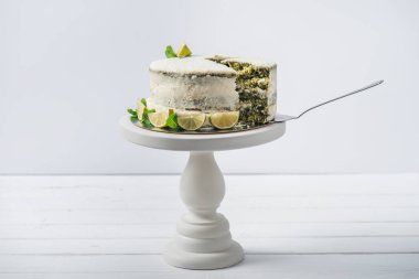 Nane yaprakları ve çizgi dilimleri üzerinde beyaz izole stand süslenmiş beyaz pasta