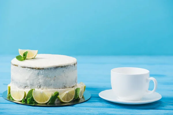 Tort Udekorowany Plastrami Limonki Pobliżu Filiżanki Herbaty Niebieskim Tle — Zdjęcie stockowe