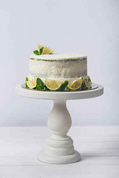 cake decorated with slices of lime on stand isolated on white