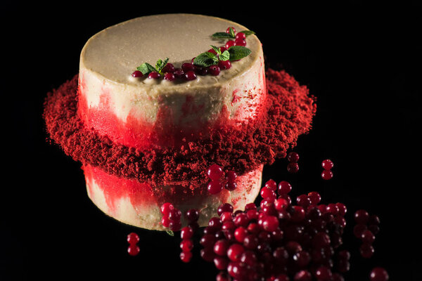 white cake decorated with mint leaves near currants isolated on black