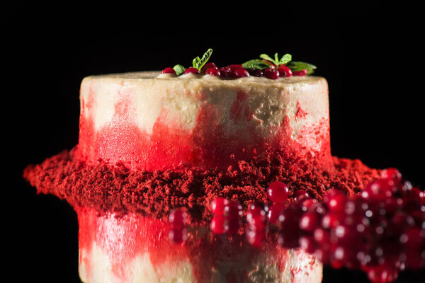 white cake decorated with mint leaves and red currants near berries isolated on black