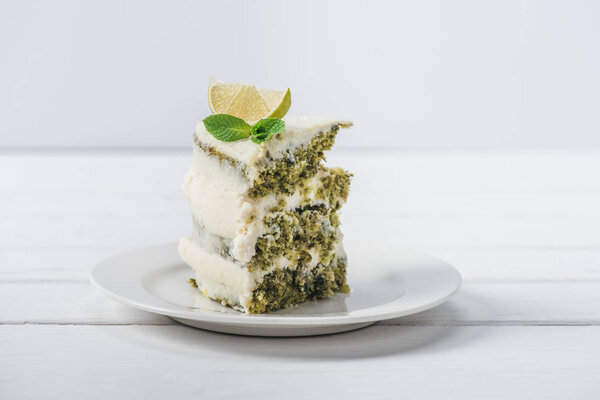 piece of white cake decorated with mint leaves and line slices isolated on white