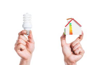 cropped view of male hands holding house model and fluorescent lamp in hands isolated on white, energy efficiency at home concept clipart