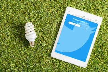 floresan lamba dijital tablet twitter uygulaması ile yakın yeşil çimen, enerji verimliliği kavramı ekranda yukarıdan