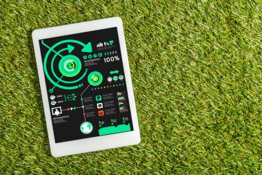 yeşil çimen, enerji verimliliği kavramı ekranda grafikler ile dijital tablet üstten görünüm