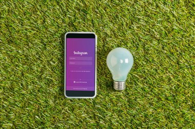 floresan lamba smartphone instagram app ile yakın yeşil çimen, enerji verimliliği kavramı ekranda yukarıdan