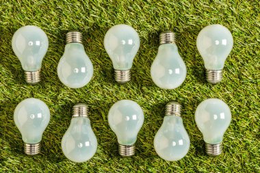 top view of fluorescent lamps on green grass, energy efficiency concept clipart