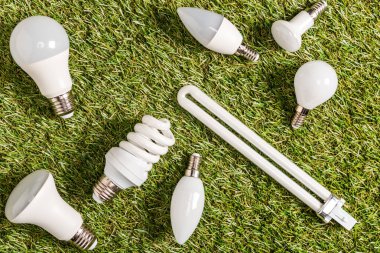top view of fluorescent lamps on green grass, energy efficiency concept clipart