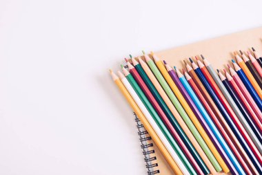 set of wooden colorful pencils on notebook on white background clipart