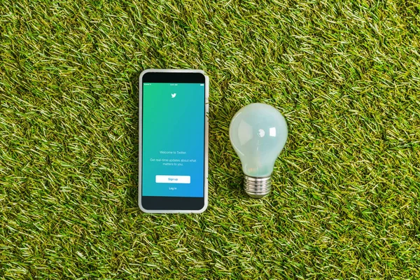 Top View Fluorescent Lamp Smartphone Twitter App Screen Green Grass — Stock Photo, Image