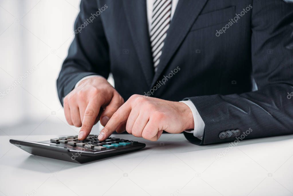 cropped view of businessman in suit using calculator on white background, energy efficiency concept