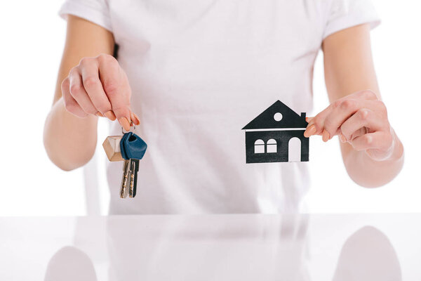 partial view of woman holding paper house and keys isolated on white, mortgage concept
