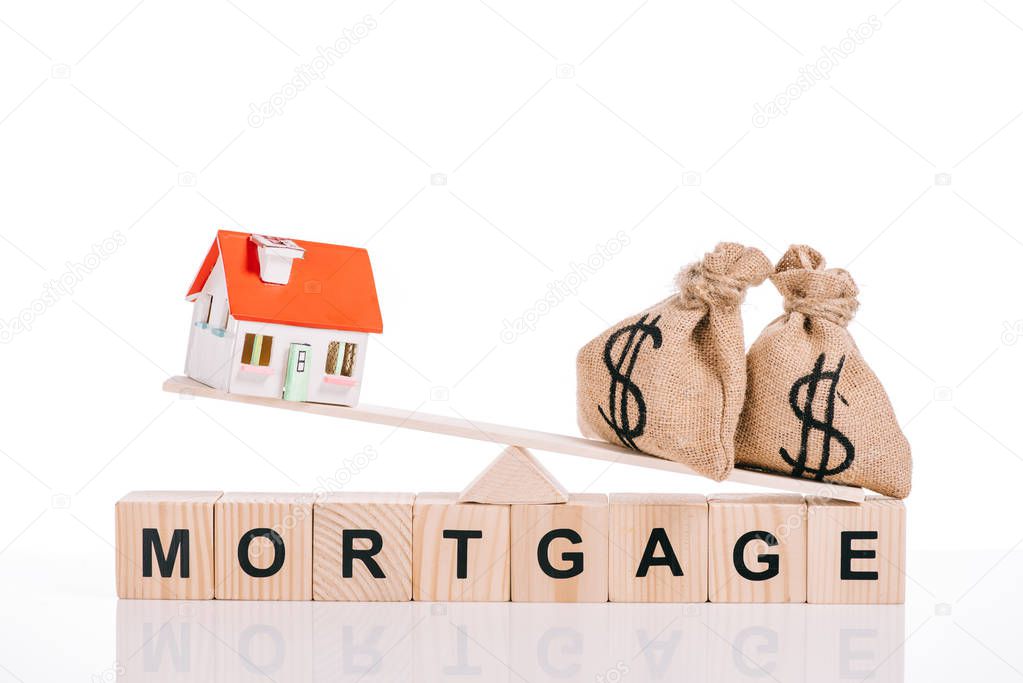 wooden blocks with mortgage lettering and scales with moneybags and house model isolated on white 