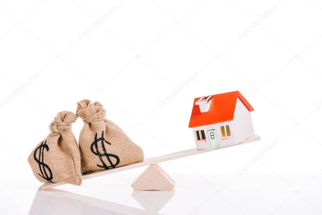 scales with moneybags and house model isolated on white, mortgage concept