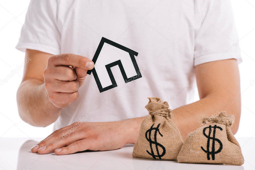 cropped view of man holding paper house near moneybags isolated on white, mortgage concept