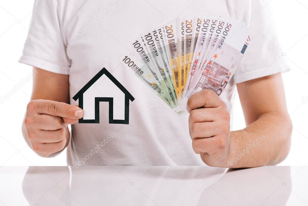 cropped view of man holding cash and paper house isolated on white, mortgage concept