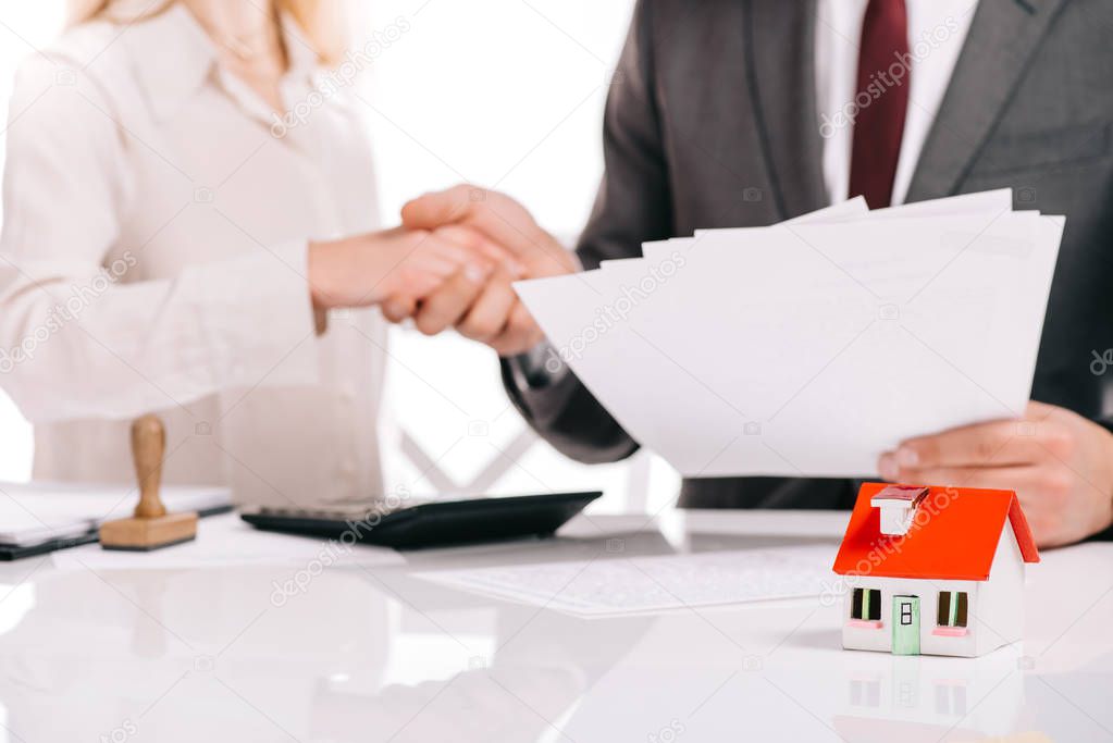 cropped view of businessman and businesswoman shaking hands isolated on white, mortgage concept