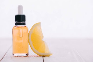 CBD petrol şişe damlalık ve ahşap yüzeyi üzerinde beyaz izole limon dilimi ile