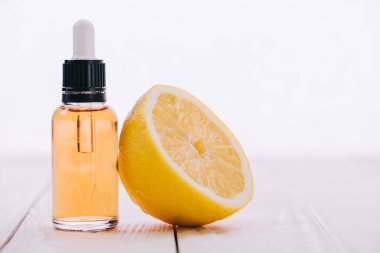 CBD petrol şişe damlalık ve ahşap yüzeyi üzerinde beyaz izole limon yarısı ile