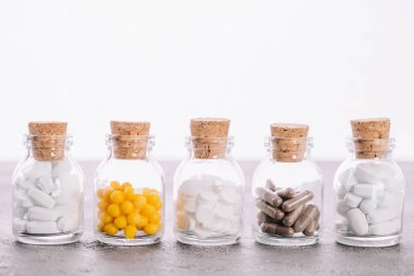 row of bottles with corks and different pills isolated on white clipart