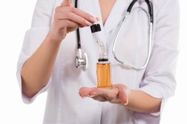 Kırpılan kadın doktor açılış şişeyle petrol ve üzerinde beyaz izole damlalık görünümünü