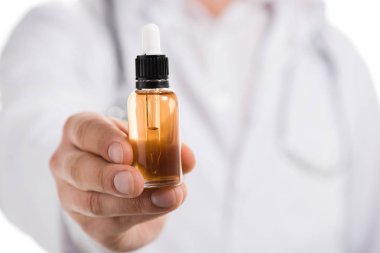 Kırpılan görünümünü el ile üzerine beyaz izole esans şişesi tutan erkek doktor