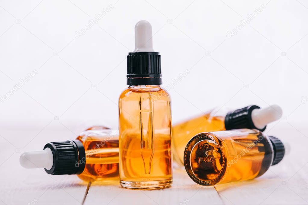 cannabidiol oil in bottles with droppers on wooden surface with copy space isolated on white