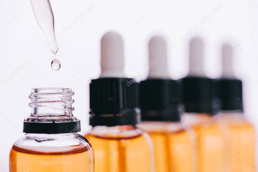 selective focus of cbd oil drop with dropper isolated on white