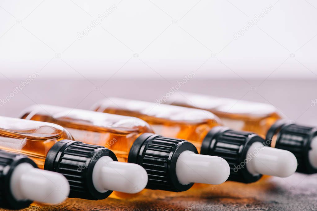 Close up of cbd oil in bottles with droppers on grey surface