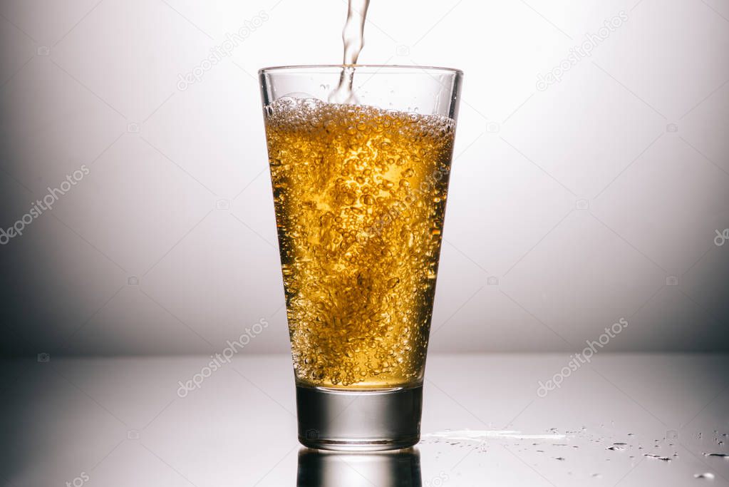 full glass of tea and splashes on grey background 