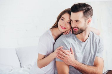 Yetişkin mutlu çift kucaklayan ve yatakta gülümseyen nazik