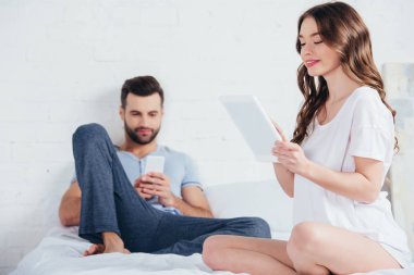 Genç çift yatağa oturma ve yatak odasında araçları kullanma