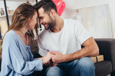 Genç adam evde gülümseyen kız ile elele