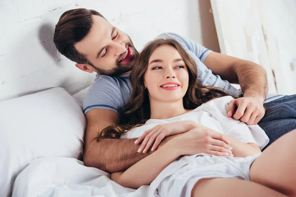 Jovem Casal Amoroso Adulto Sorrindo Abraçando Gentilmente Cama — Fotografia de Stock