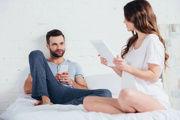 Young Couple Sitting Bed Gadgets Talking Bedroom — Stock Photo, Image