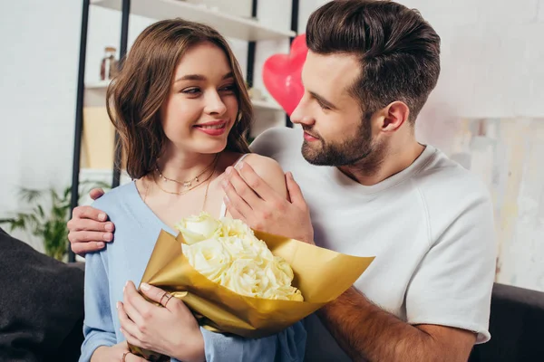 若い男のバラ花束とハグのガール フレンド 聖バレンタインの日を祝う幸せなカップル — ストック写真