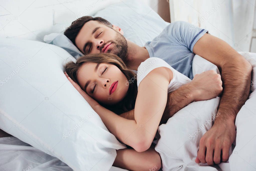 adult couple sleeping on soft white bedding in bedroom