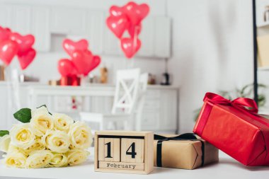 arka plan üzerinde kalp şeklinde balonlu masaya hediye kutuları şeritler, gül buketi ve 14 Şubat ile takvim tarih