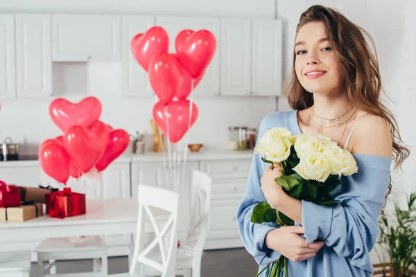 一个微笑的女孩在房间里拿着花束的选择性焦点 房间里装饰着心形的气球 — 图库照片