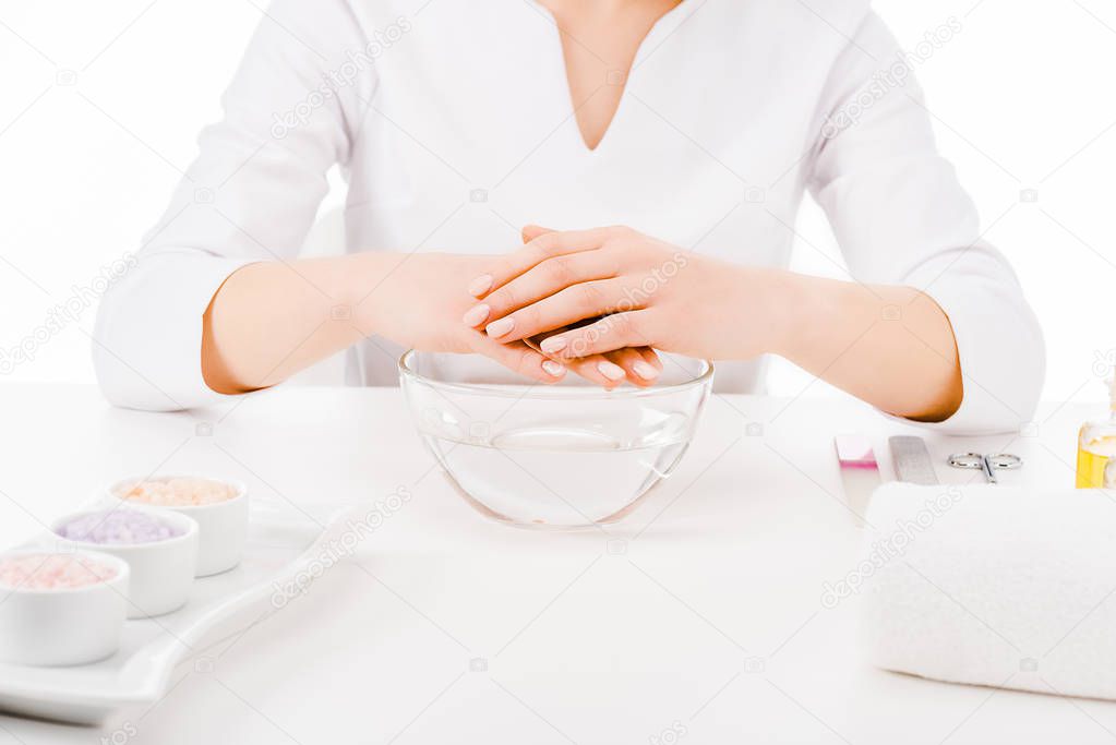 Cropped view of manicurist in uniform doing hand treatment isolated on white