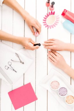 Top view of manicurist applying pink nail polish clipart