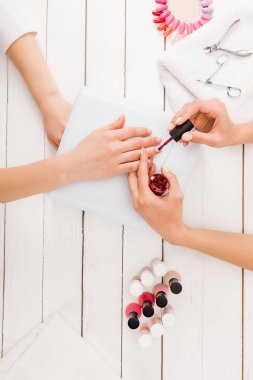 Top view of manicurist applying red nail polish clipart