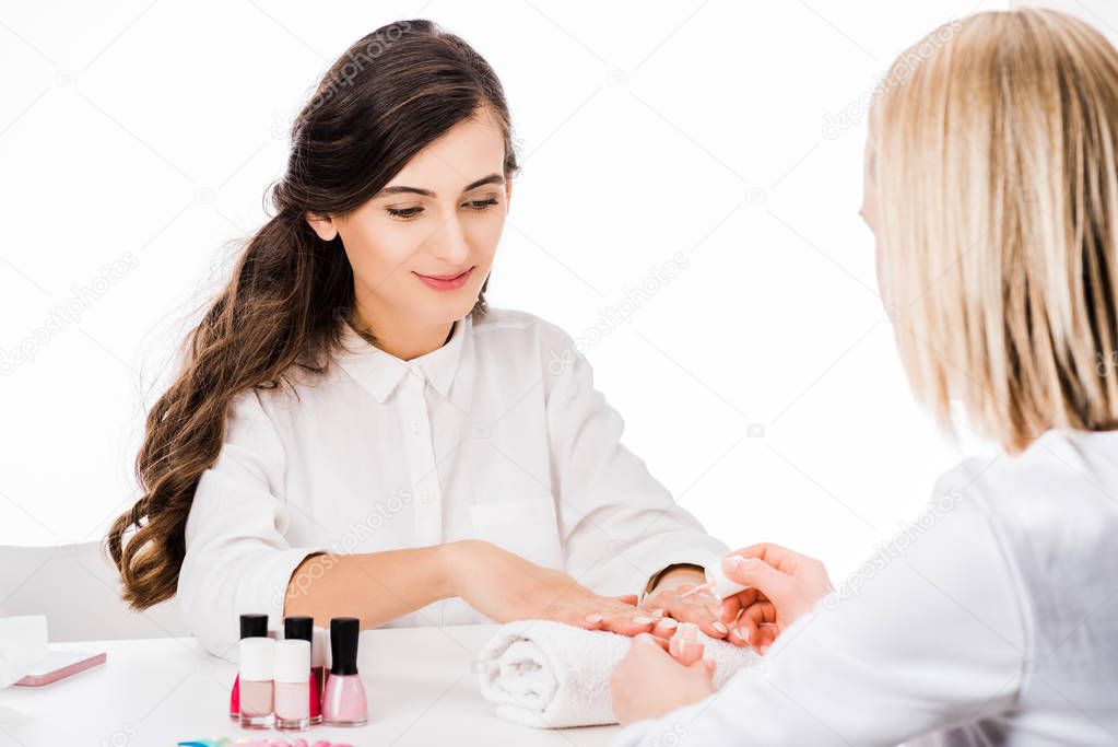 Attractive brunette woman looking at hands during manicure isolated on white